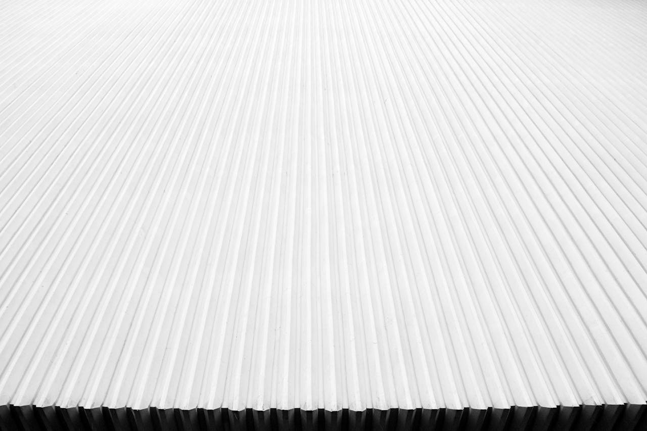 Abstract close-up of a modern corrugated metal roof with linear patterns in white.